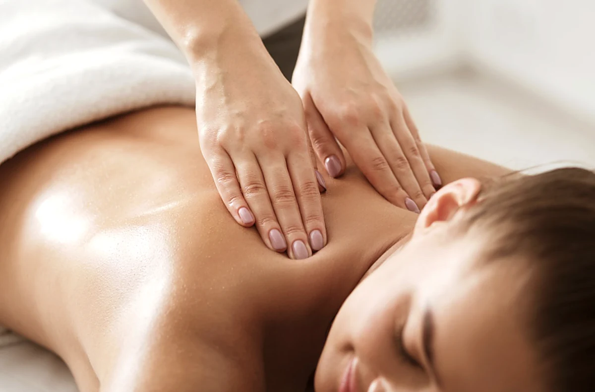 A therapist massaging a guest's upper back